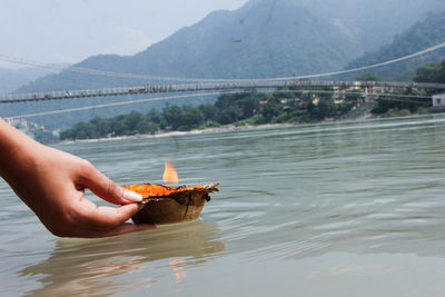 Close-up of person holding diya on water surface