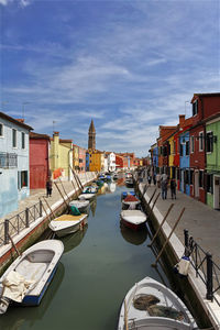 Boats moored in canal amidst buildings in city