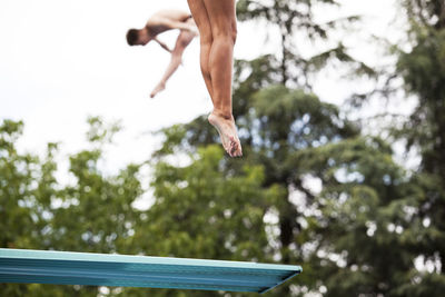 Low section of man jumping over diving board