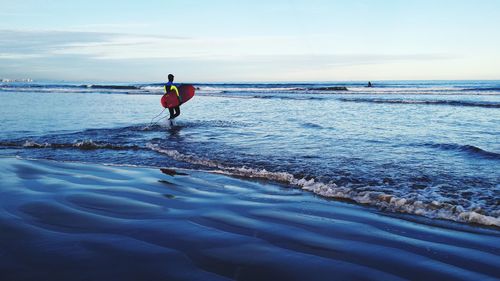 Male surfer walking in calm blue sea