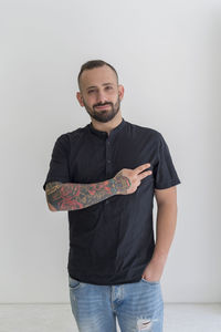 Portrait of young man gesturing peace sign against white background