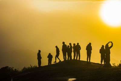 Silhouette people standing on land against sky during sunset