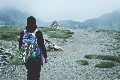 Rear view of woman standing on mountain during foggy weather