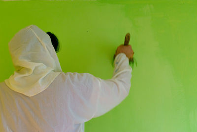 Unrecognizable person holding a paint brush and paints the wall with gray colour. diy concept.