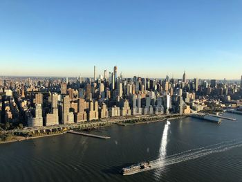 Aerial view of buildings in city by river against sky