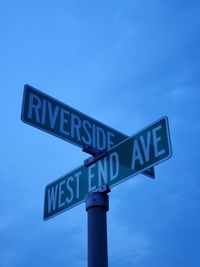 Low angle view of road sign against blue sky