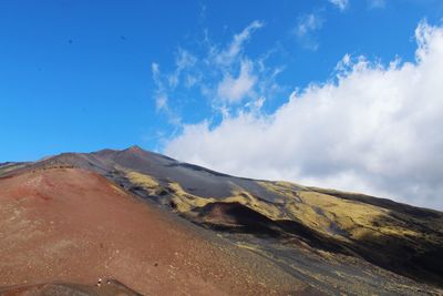 Scenic view of volcanic mountain against blue sky