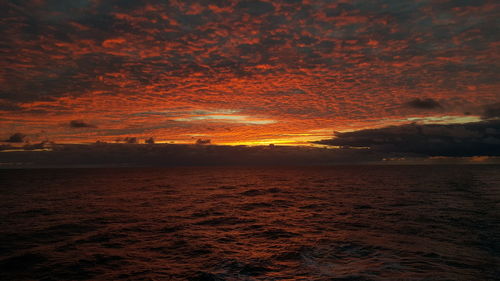 Scenic view of sea against dramatic sky during sunset