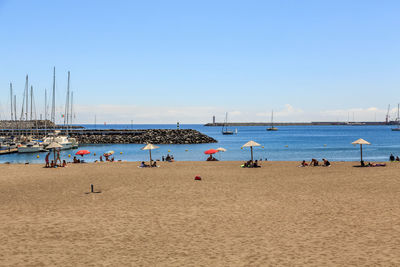 People at beach against blue sky