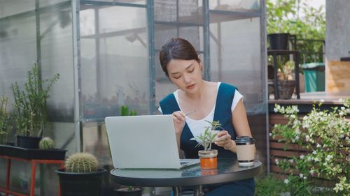 Young woman using mobile phone while sitting on table