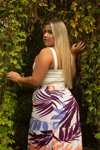 Young woman standing against plants