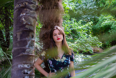 Portrait of young woman with tree trunk in forest