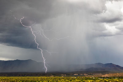 Lightning over landscape against cloudy sky