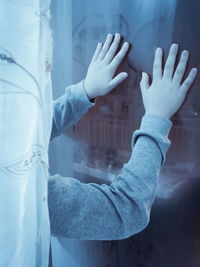 Cropped hands of person on glass window