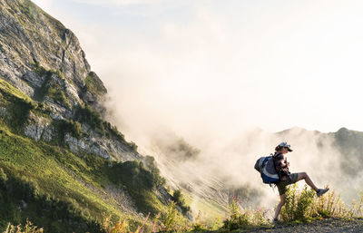 Rear view of man standing on mountain against sky