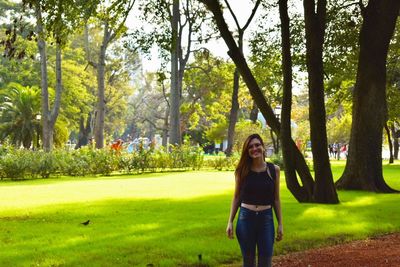 Portrait of young woman standing against trees