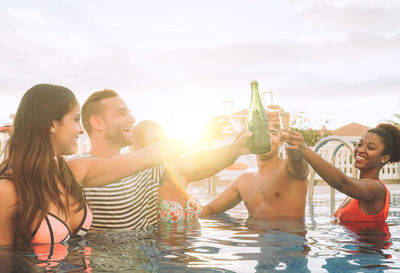 Happy friends toasting drinks in swimming pool