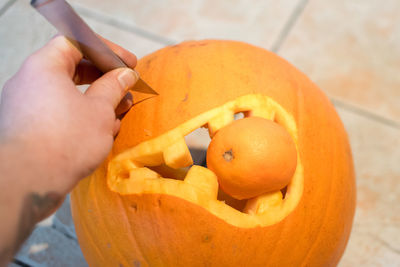 Close-up of  hand holding knife while carving pumpkin