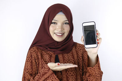 Portrait of smiling young woman holding mobile phone