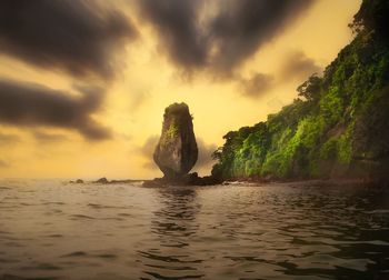 Rocks in sea against sky during sunset