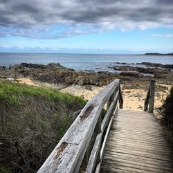 Boardwalk leading towards sea against sky