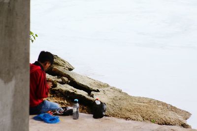 Woman sitting on retaining wall by rock