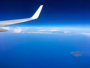 Airplane flying over sea against blue sky