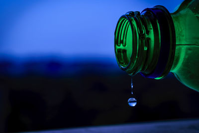 Close-up of water falling from faucet against blue sky