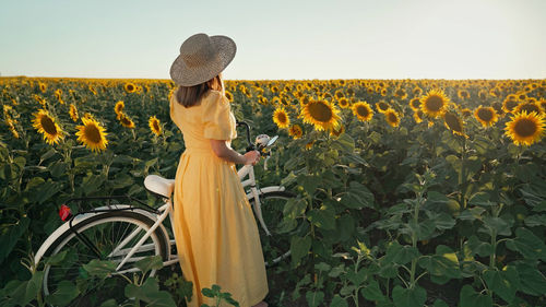 Rear view of woman standing on field against sky