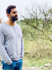 Portrait of young man standing against trees