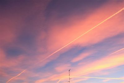 Low angle view of vapor trails in sky during sunset