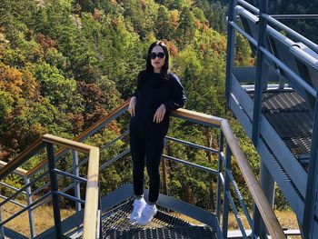 Full length portrait of woman standing on footbridge