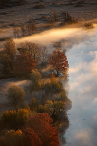 Scenic view of river against sky during sunrise, trees surrounded by clouds