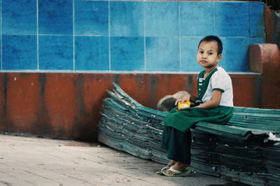 Rear view of man sitting on wall