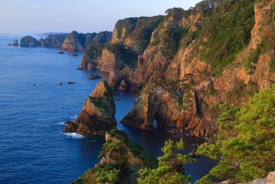 Scenic view of rocks by sea against sky