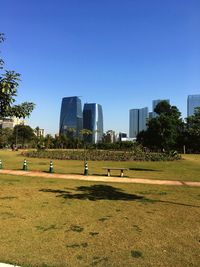 People on field by city against clear sky