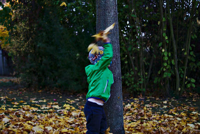 Boy throwing leaves in forest during winter