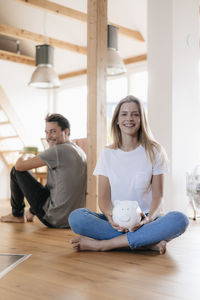 Couple sitting in new home with a piggy bank