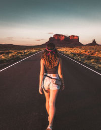 Rear view of woman standing on road against sky