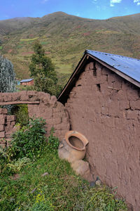 Built structure on field by mountain against sky