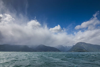 Scenic view of sea by mountains against sky