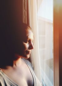 Portrait of young woman looking through window