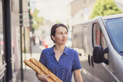 Young woman buying a french baguette