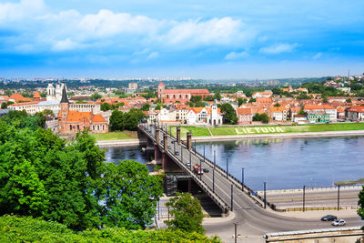 Bridge over river amidst buildings in city against sky