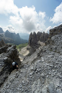 Rear view of person on rocks by mountains against sky