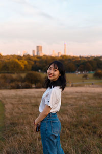 Portrait of smiling young woman standing on field