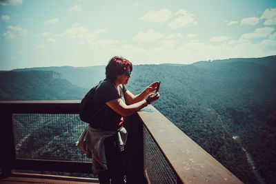 Man photographing while standing on railing