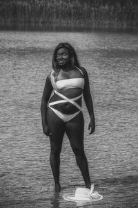 Portrait of woman in bikini standing against sea