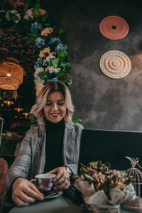 Portrait of young woman holding flowers on table