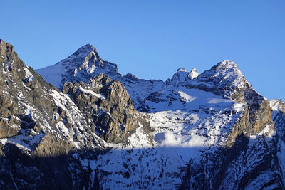 Panoramic view of snowcapped mountains against clear blue sky